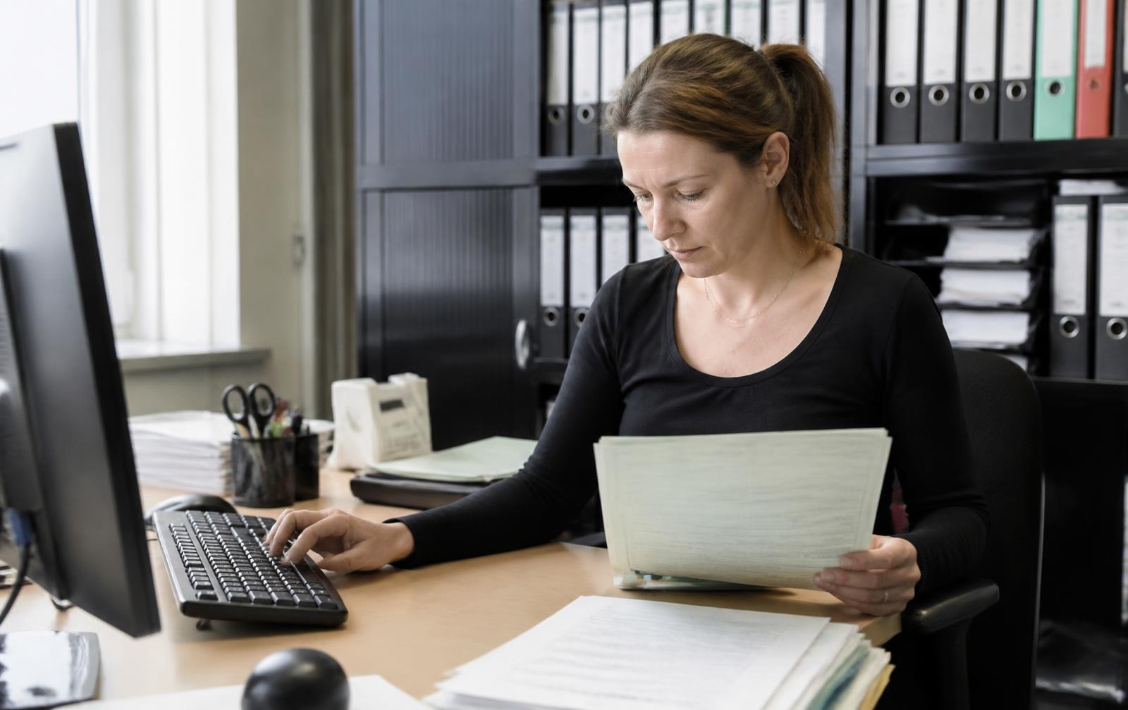 Mitarbeiterin geht einen wiederkehrenden Arbeitsablauf am Schreibtisch durch – Betriebsabläufe in Software abbilden