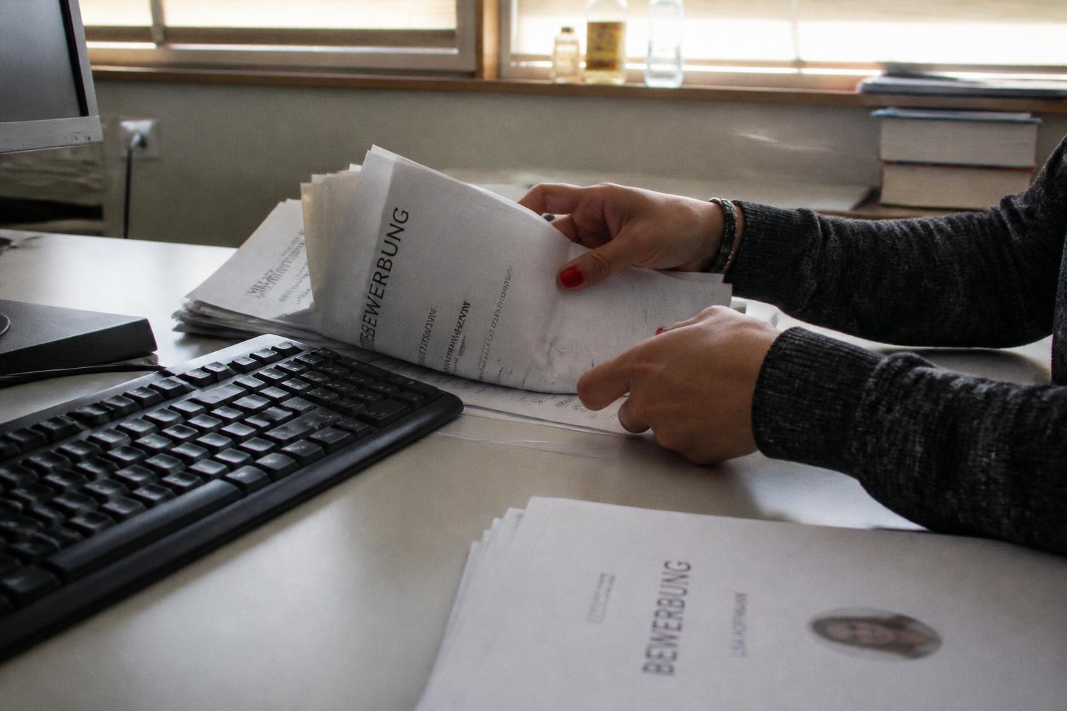 Personalverantwortliche sichtet Bewerbungsunterlagen am Schreibtisch – KI im Personalwesen
